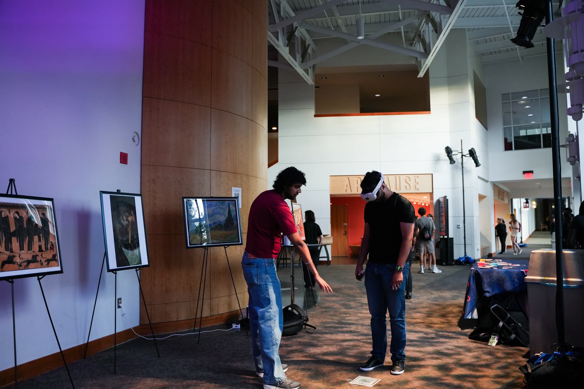 Arindam points a headset-wearing visitor toward a printed marker on the floor.